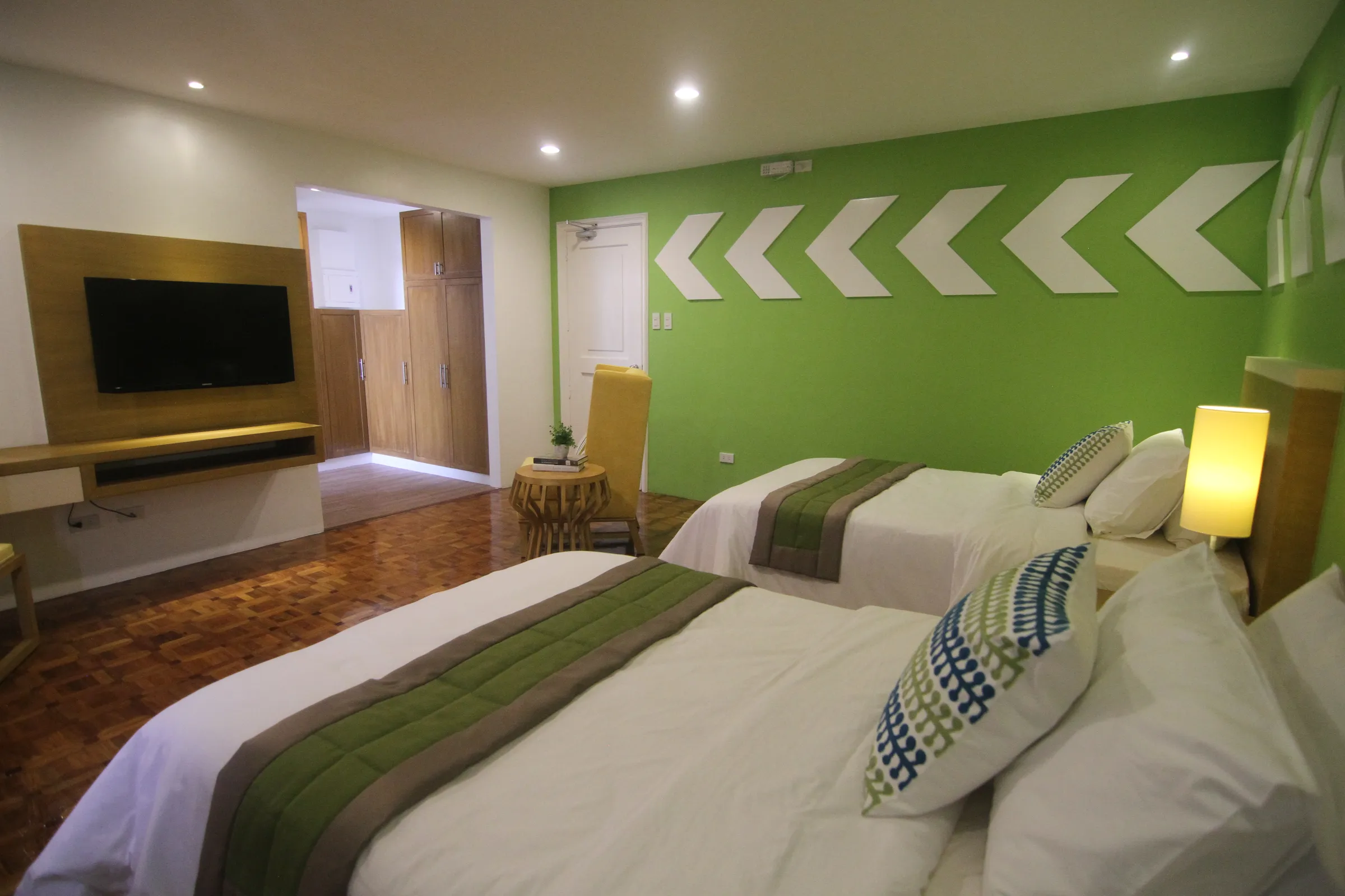 A Deluxe Twin room with two single beds and yellow accent chairs.