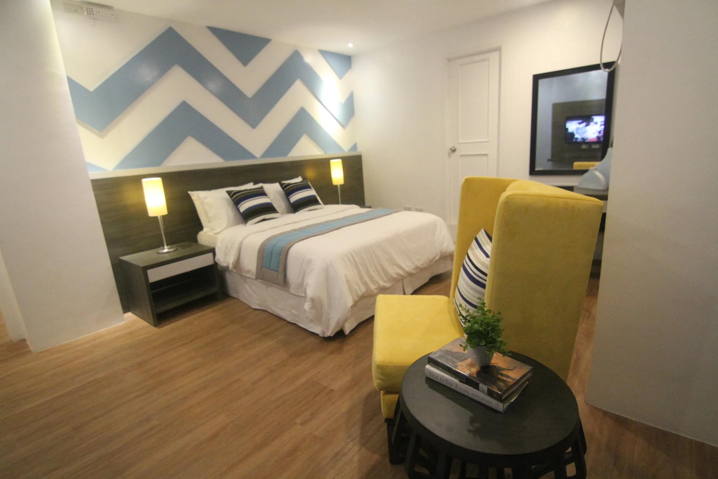 The Deluxe Queen room's queen bed, vanity and wall-mounted TV.