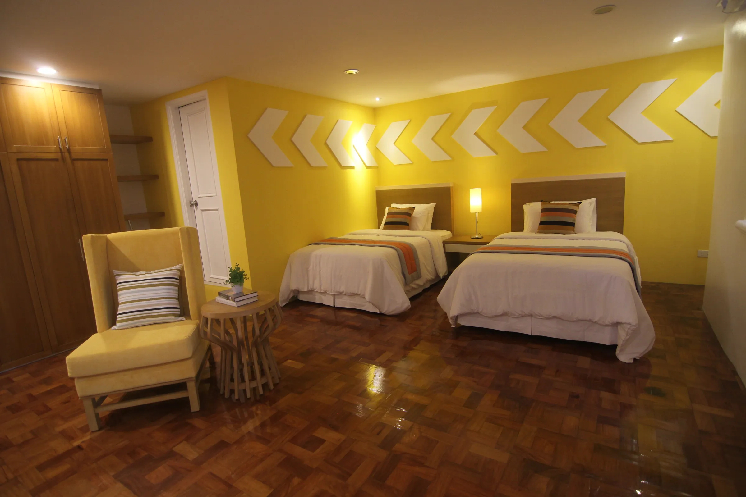 The Deluxe Triple room with warm yellow walls and wood floors.